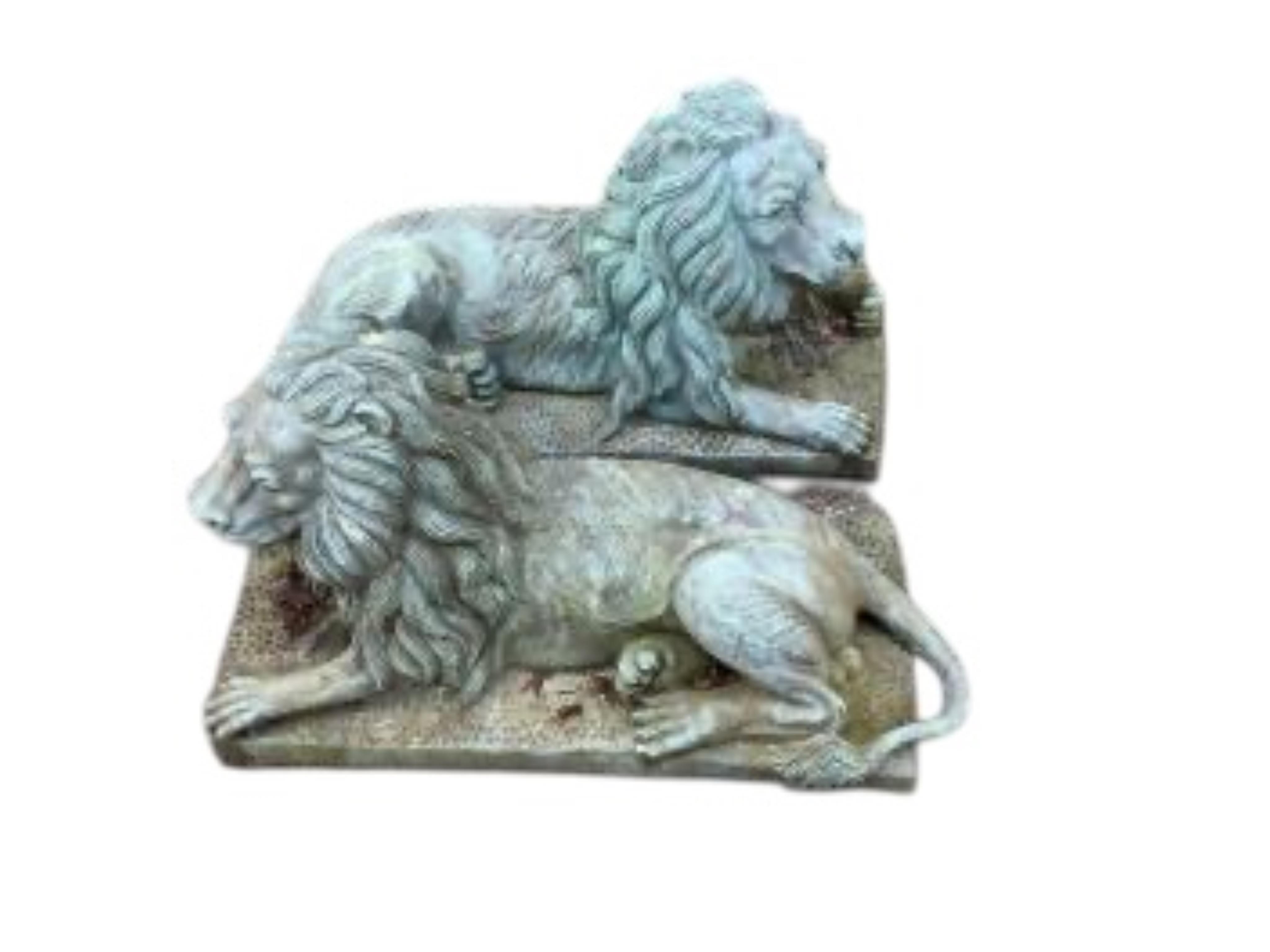 A pair of green patinated cast iron recumbent lions, length 46cm, height 24cm